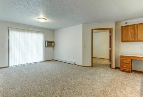 A room with a desk and a window with blinds.