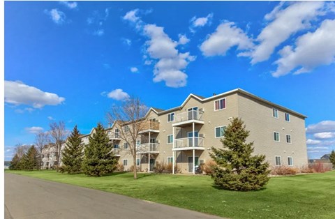 A large apartment building with a green lawn in front.