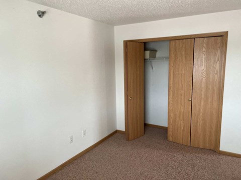 A room with a brown carpet and a white wall with a wooden door.