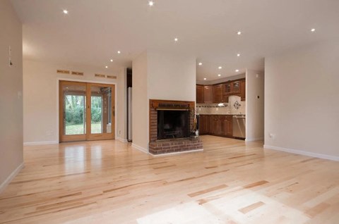 an empty living room with a fireplace and a kitchen