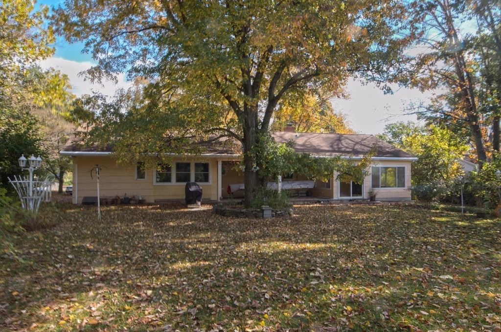 a small yellow house with a large tree in the yard