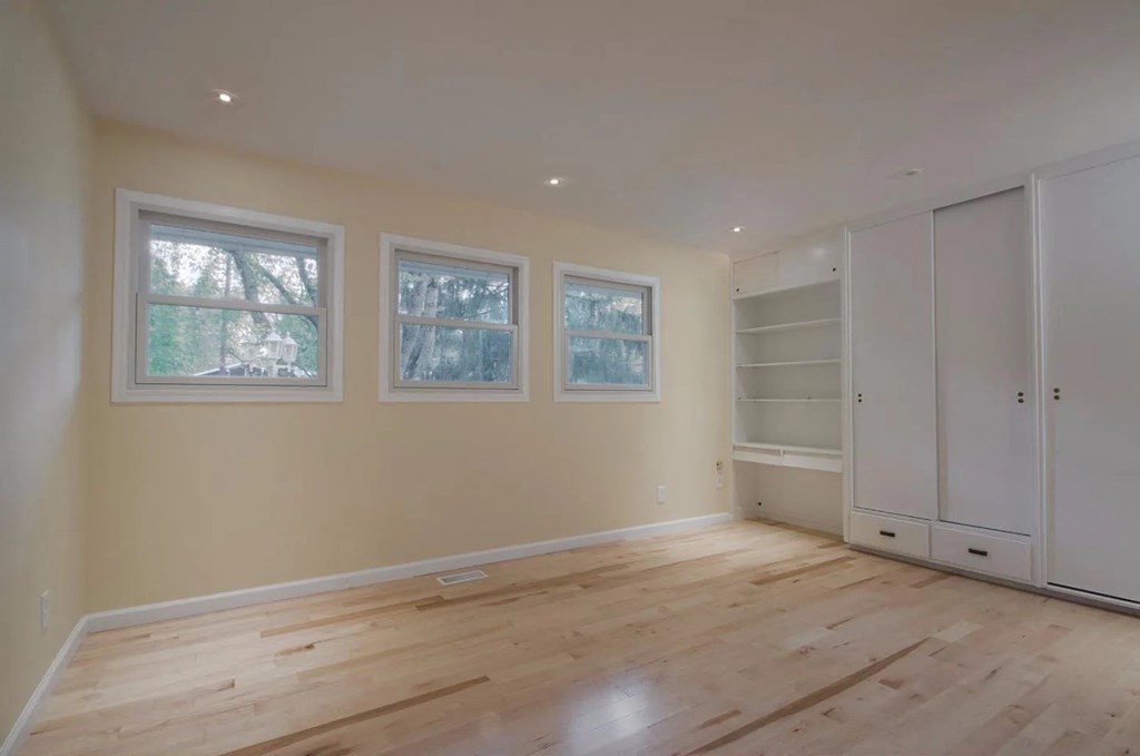 a living room with a wooden floor and three windows