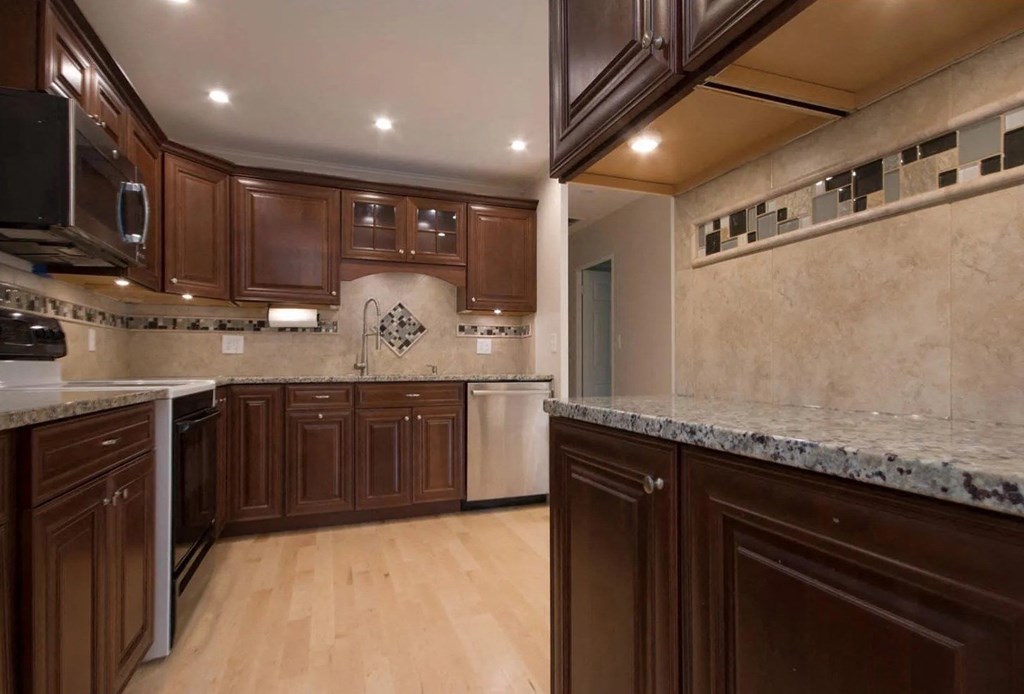 a large kitchen with marble counter tops and wooden cabinets