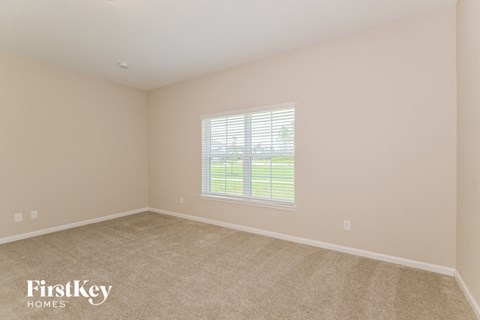 a bedroom with a large window and a carpeted floor