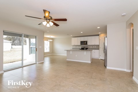 A spacious kitchen and living room with a ceiling fan and sliding glass doors.
