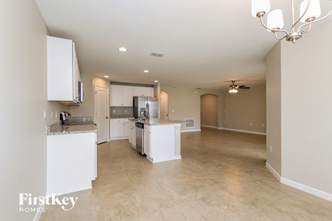 A spacious kitchen with white cabinets and a dining area with a table and chairs.