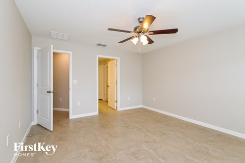 A spacious room with a ceiling fan and two doors.