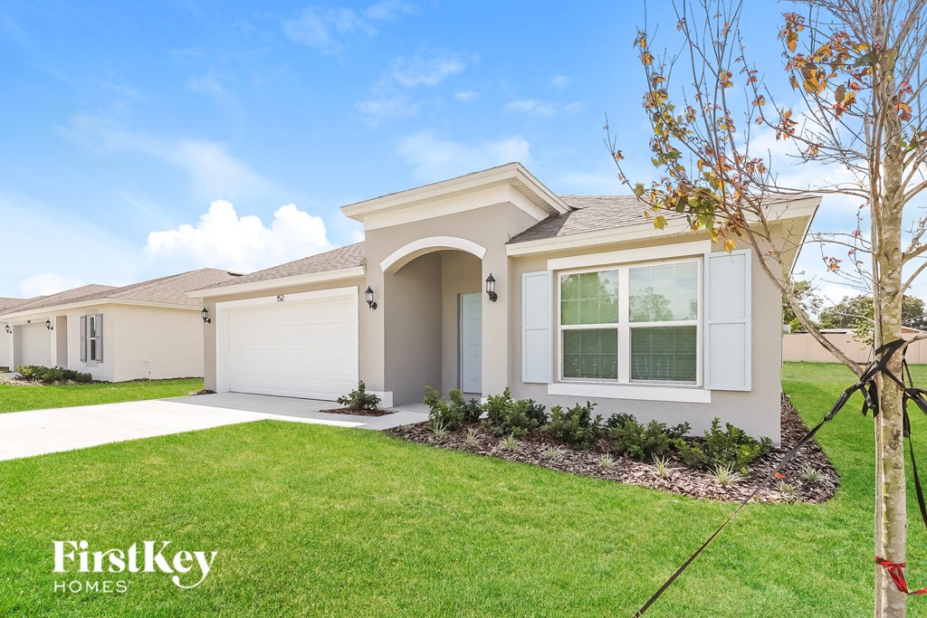 a beige house with a garage and a lawn