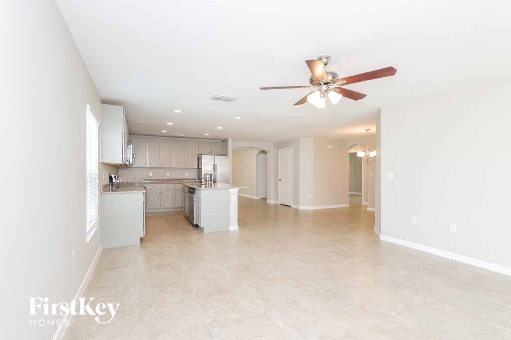 a spacious living room and kitchen with a ceiling fan