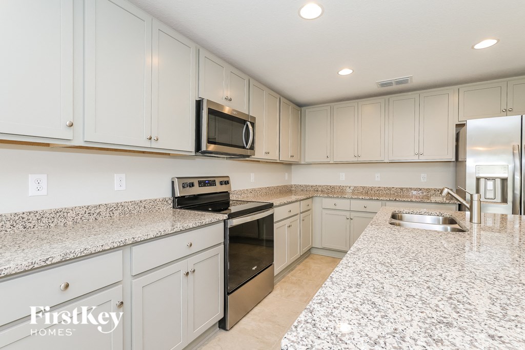 a white kitchen with granite counter tops and stainless steel appliances