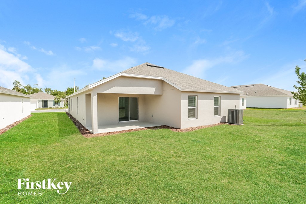 a beige house with a green lawn and a blue sky