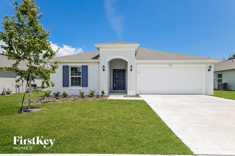 a white house with a garage door and a lawn