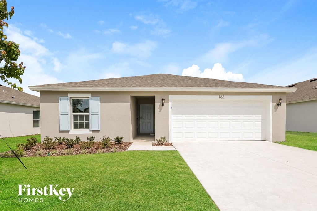 a beige house with a garage door and a lawn