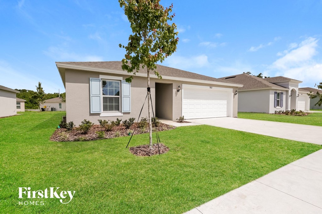 a beige house with a tree in the front yard