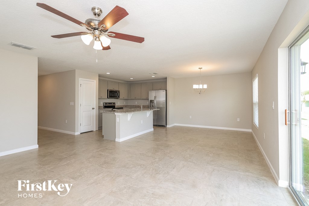 an empty kitchen and living room with a ceiling fan