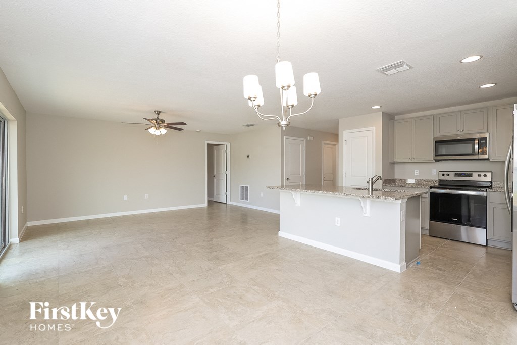 an empty kitchen and living room with a counter top island and a ceiling fan