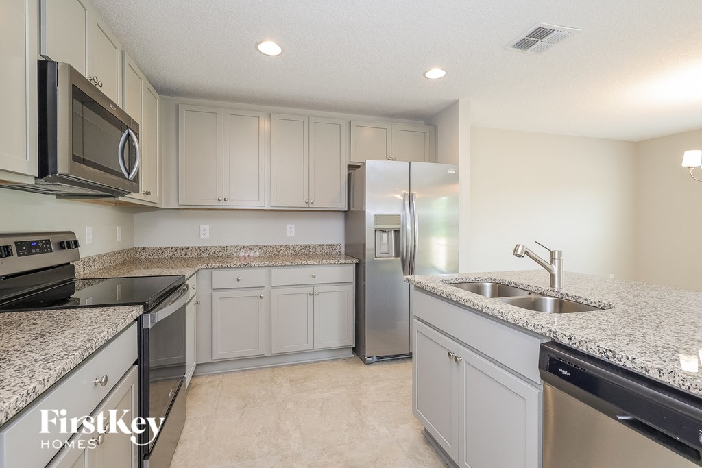 a kitchen with white cabinets and granite counter tops and stainless steel appliances