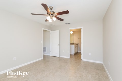 a spacious living room with a ceiling fan and tile flooring