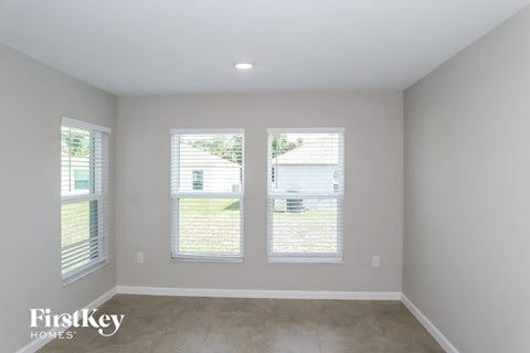 a living room with three windows and a cement floor