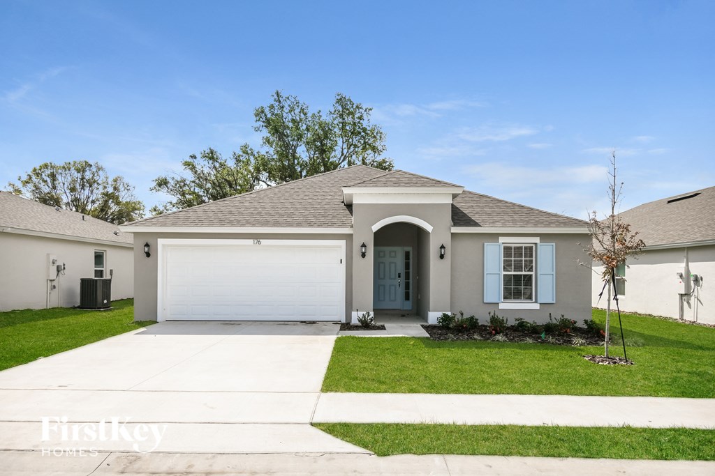 a white house with a garage door and a lawn