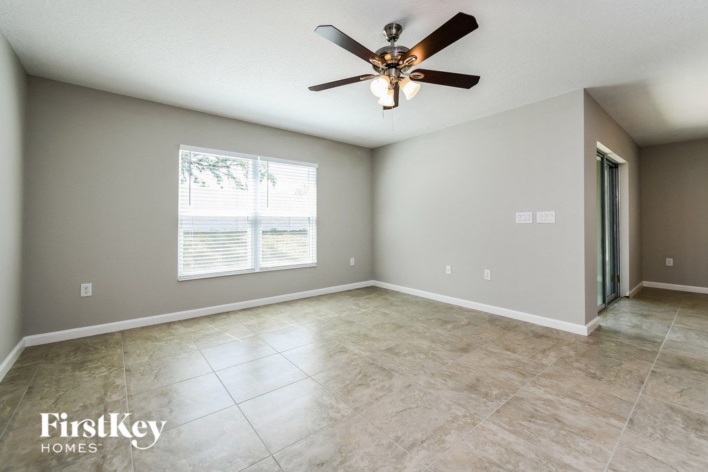 the spacious living room with tile flooring and a ceiling fan