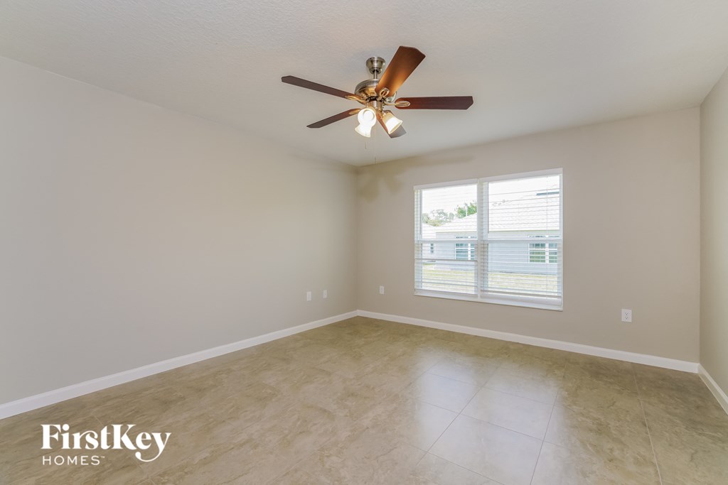 an empty living room with a ceiling fan and a window