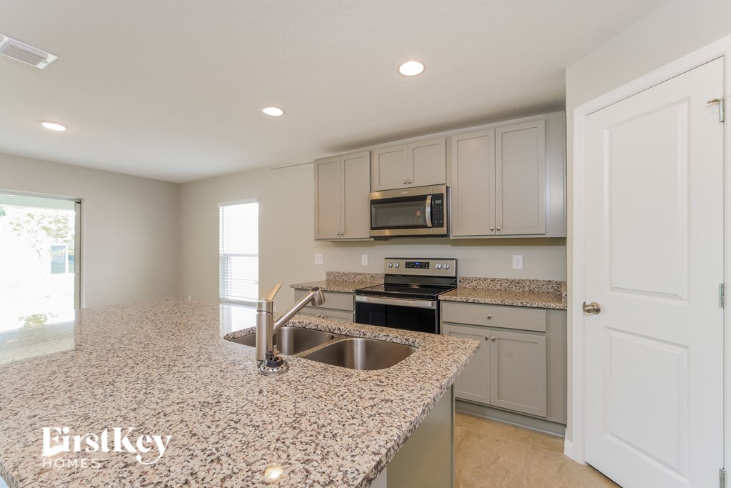 a kitchen with granite counter tops and white cabinets and a sink