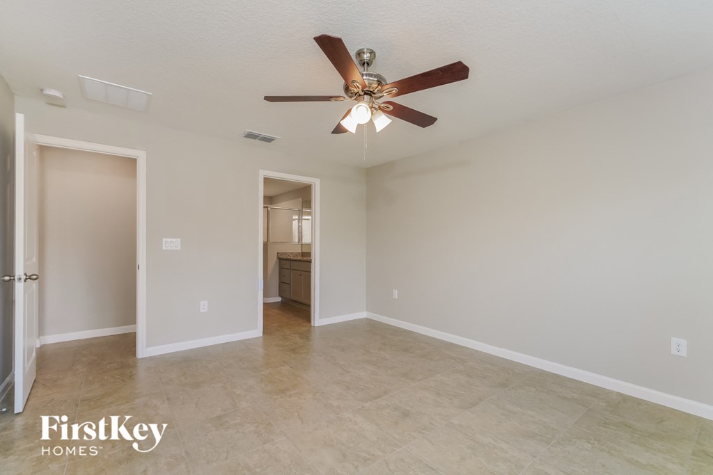 the spacious living room with ceiling fan and tile flooring