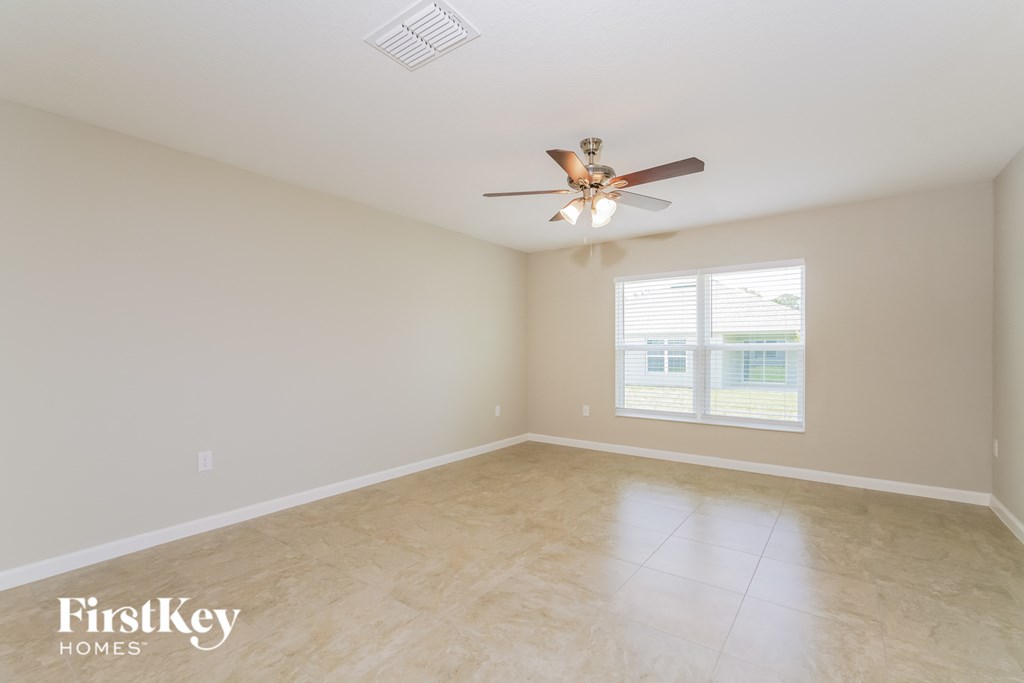 a clean and empty room with a ceiling fan and a window
