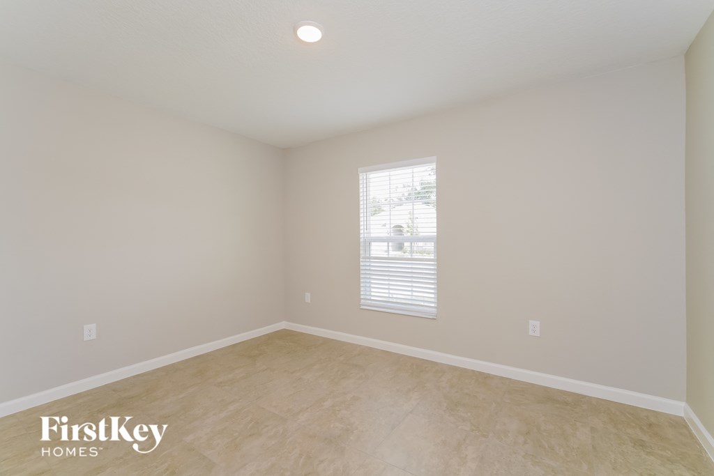 the second bedroom has a large window and beige flooring