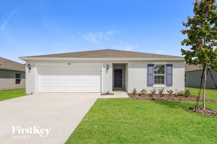 a white house with a garage door and a lawn