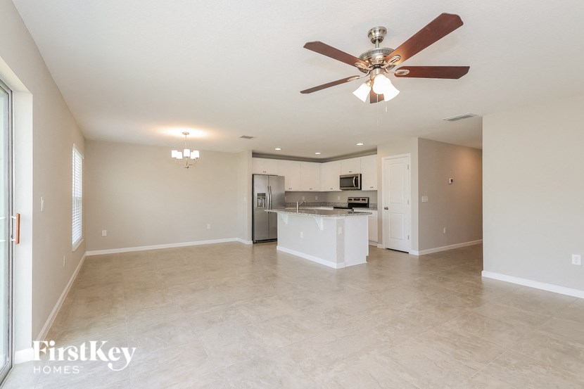 an empty living room and kitchen with a ceiling fan