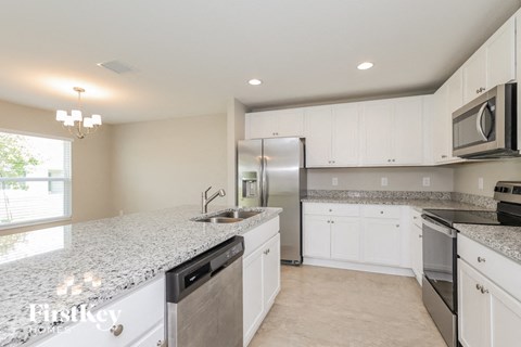 a white kitchen with granite counter tops and stainless steel appliances