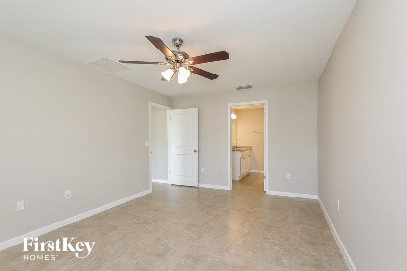 a large empty living room with a ceiling fan and a bathroom
