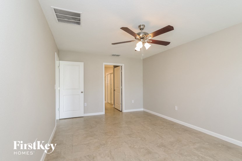 a empty living room with a ceiling fan and a door to a hallway