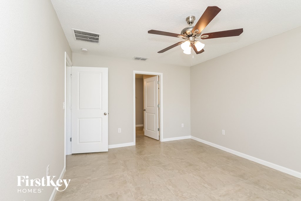 A spacious room with a ceiling fan and two doors.