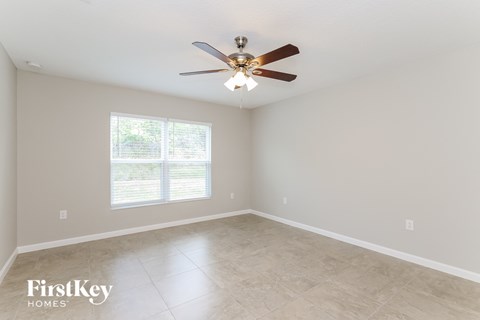 A spacious room with a ceiling fan and a window with blinds.