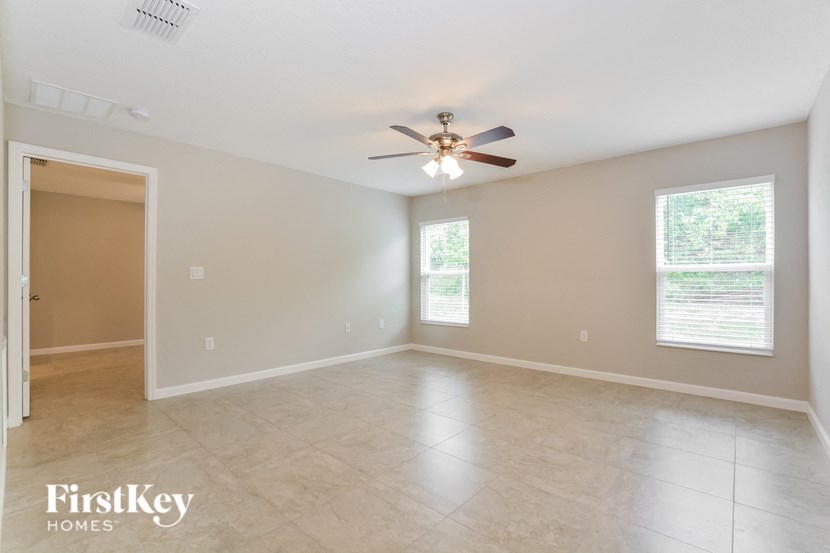 an empty living room with a ceiling fan and tiled floors