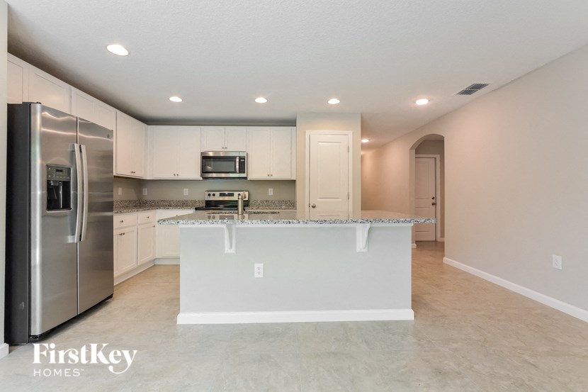 a white kitchen with a large island and stainless steel appliances