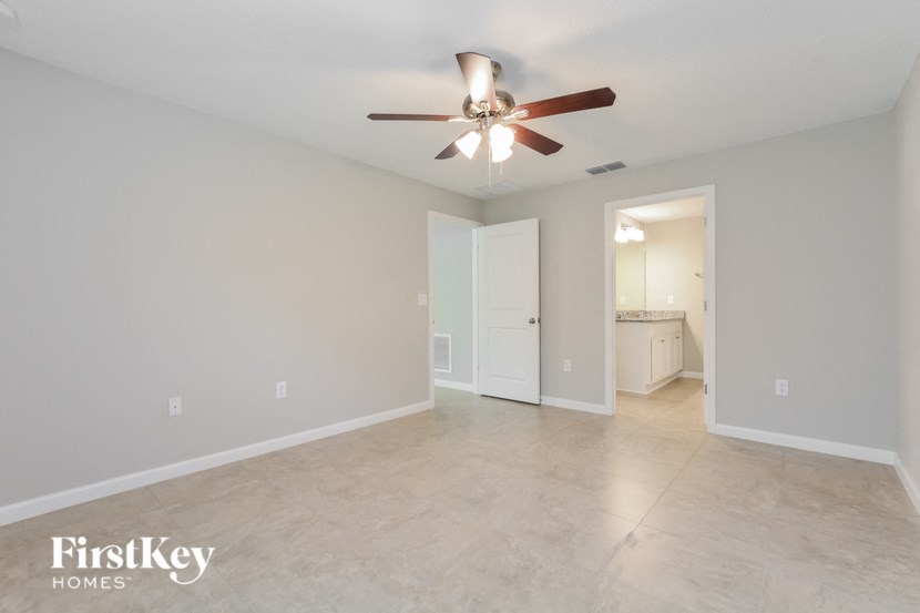 the spacious living room with ceiling fan and tile flooring