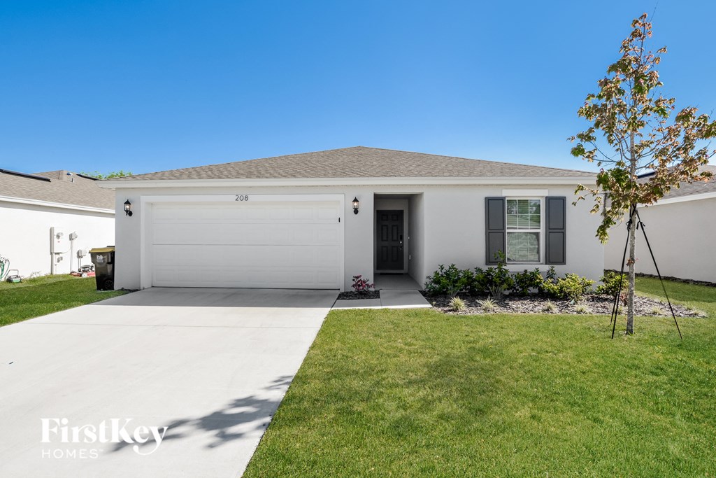 a white house with a garage door and a lawn