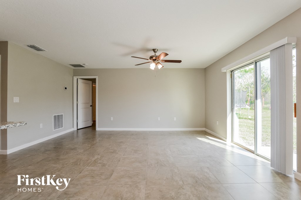 an empty living room with a ceiling fan and a large window