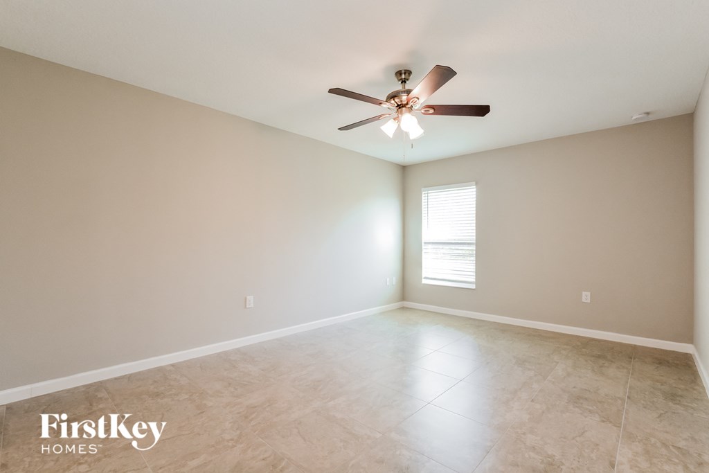 the spacious living room with ceiling fan and tiled floors