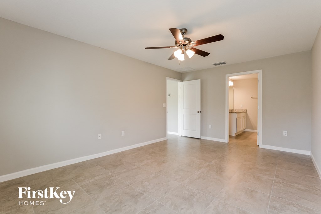 the spacious living room with ceiling fan and tile flooring