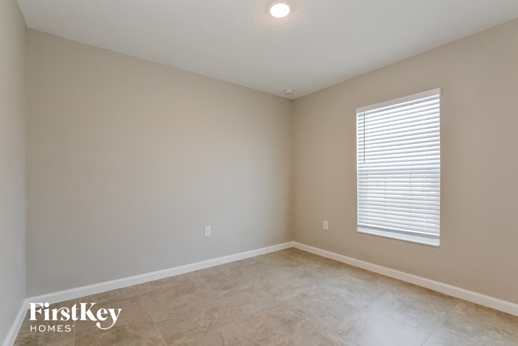 the spacious living room with beige walls and a large window