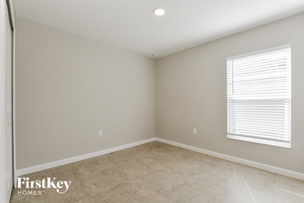 the second bedroom is spacious and has a large window and tiled floors