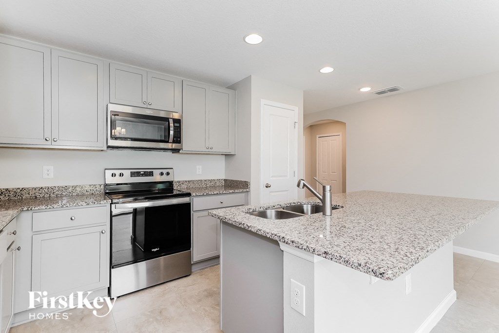 a kitchen with white cabinets and granite counter tops and a sink