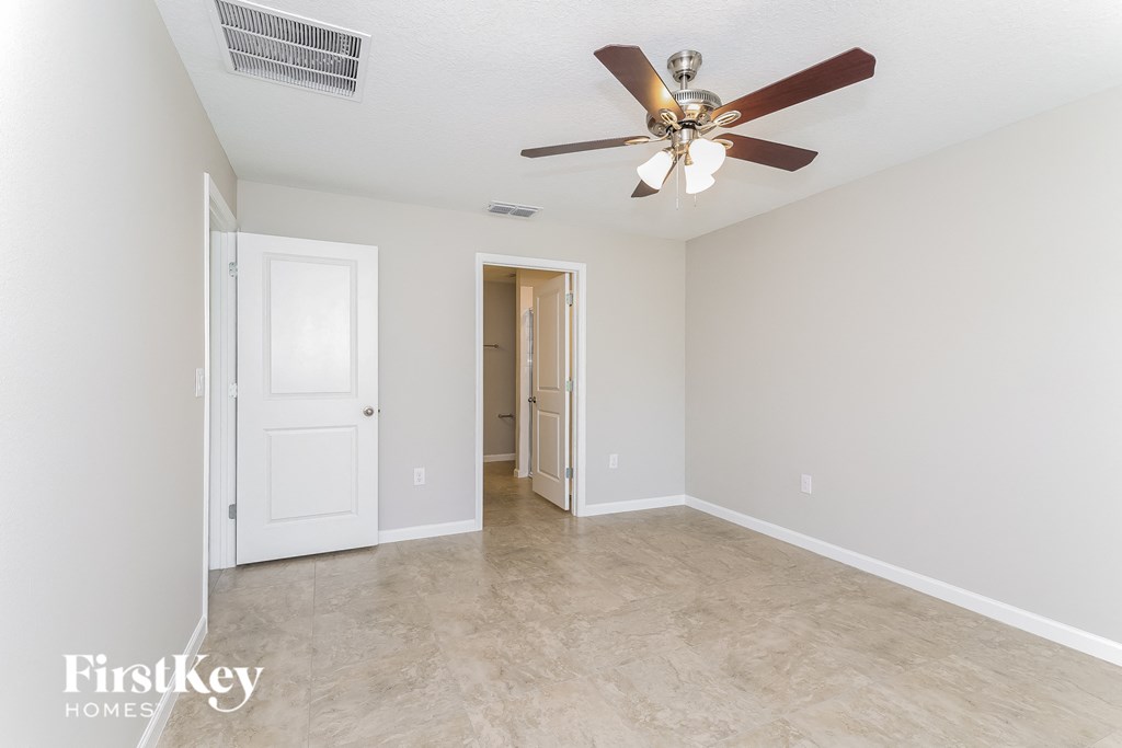 a living room with a ceiling fan and a door to a bathroom