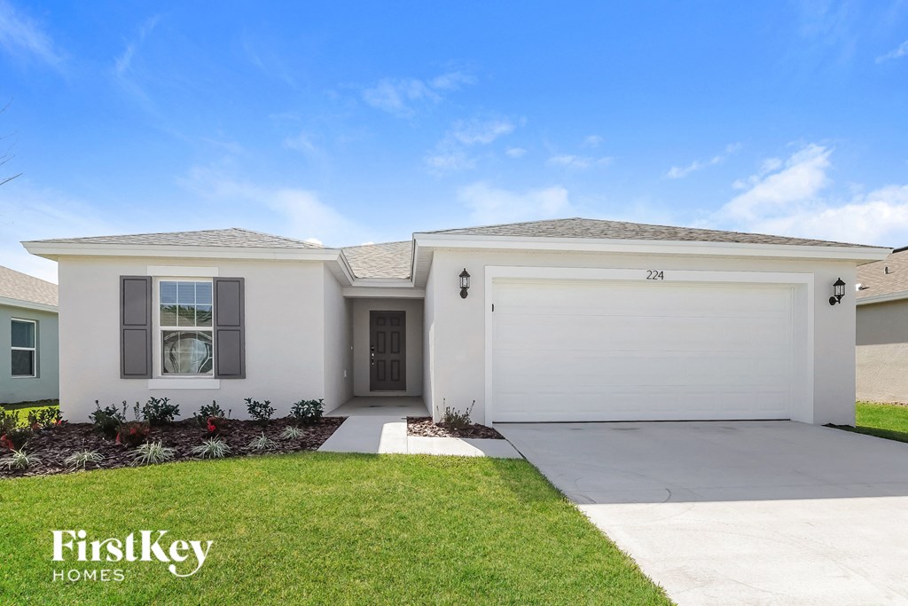 a white house with a garage door and a lawn