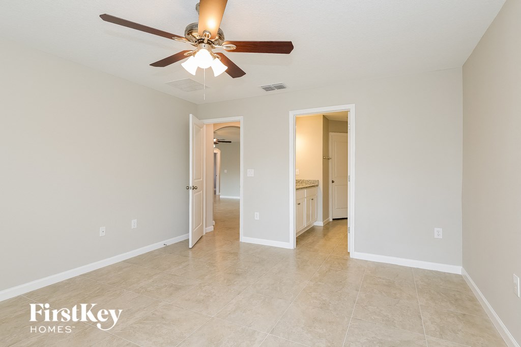 a living room with a ceiling fan and a hallway to a bathroom and a kitchen